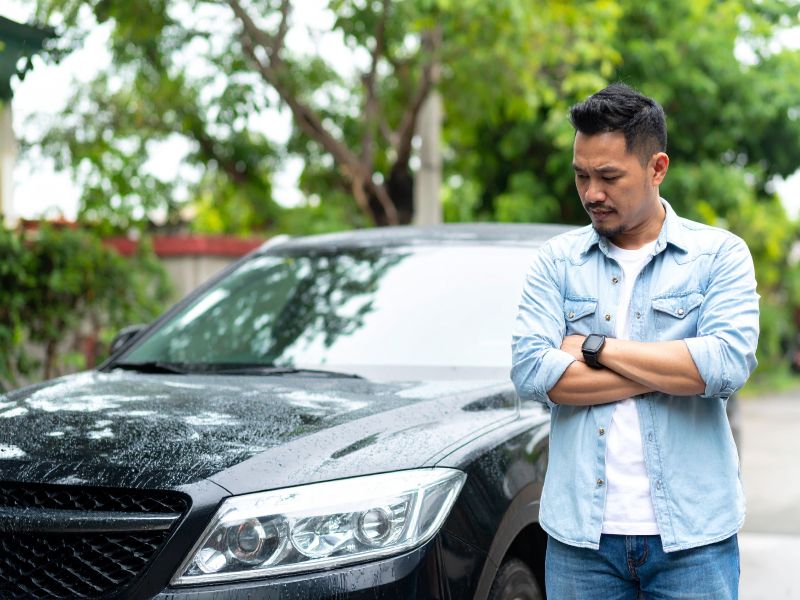 雨で車が汚れて悩む男性